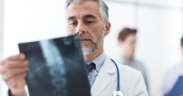 Radiologist examining a patient's x-ray, medical staff on the background, healthcare concept
